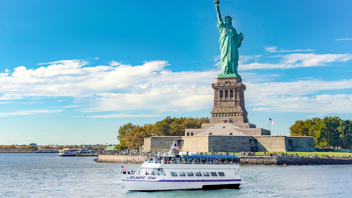 Tourists visiting the Statue of Liberty in New York on a sunny day, enjoying a 24% combo deal.