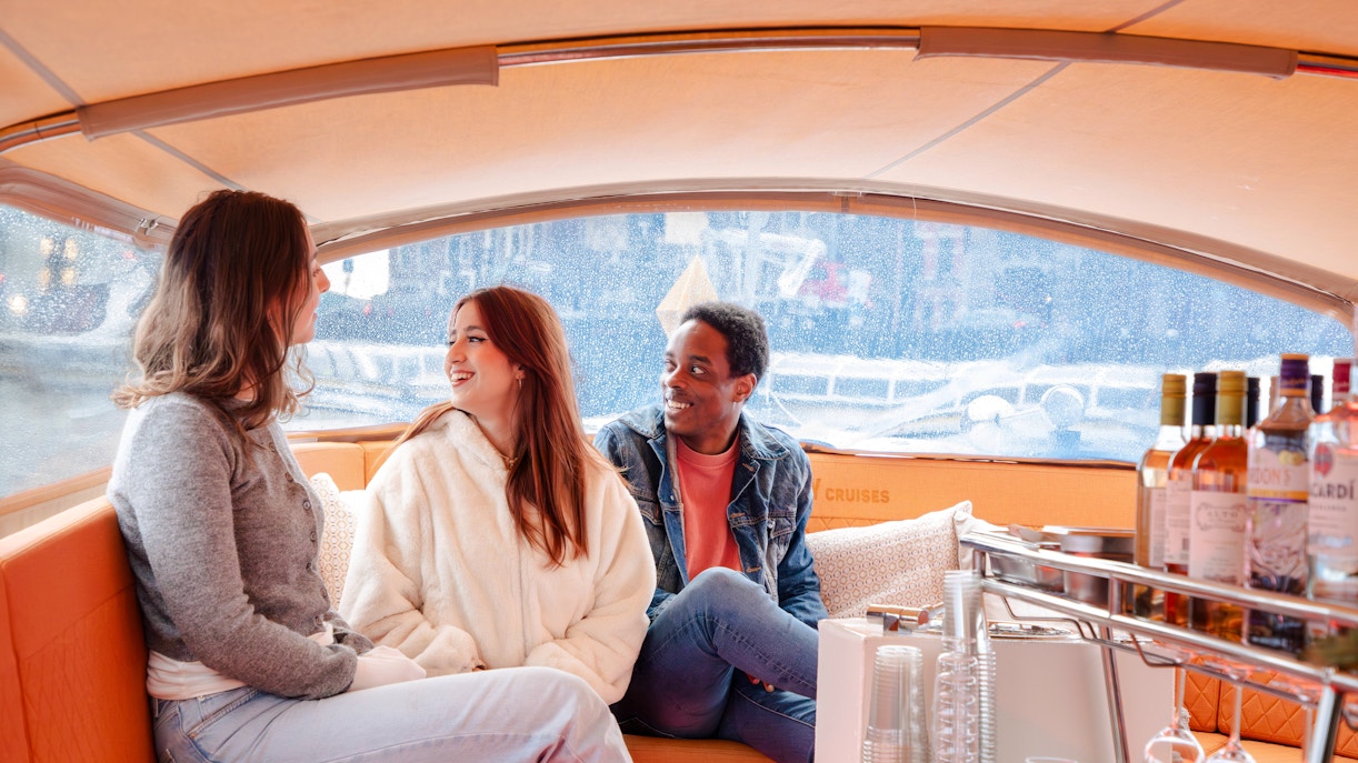 Guests enjoying an open boat cruise in Amsterdam with drinks on board.