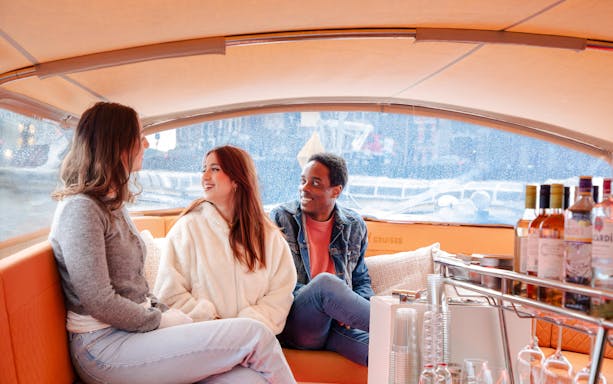 Guests enjoying an open boat cruise in Amsterdam with drinks on board.