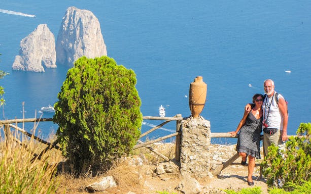 Couple enjoying view of Faraglioni rocks on Capri Island, Italy.