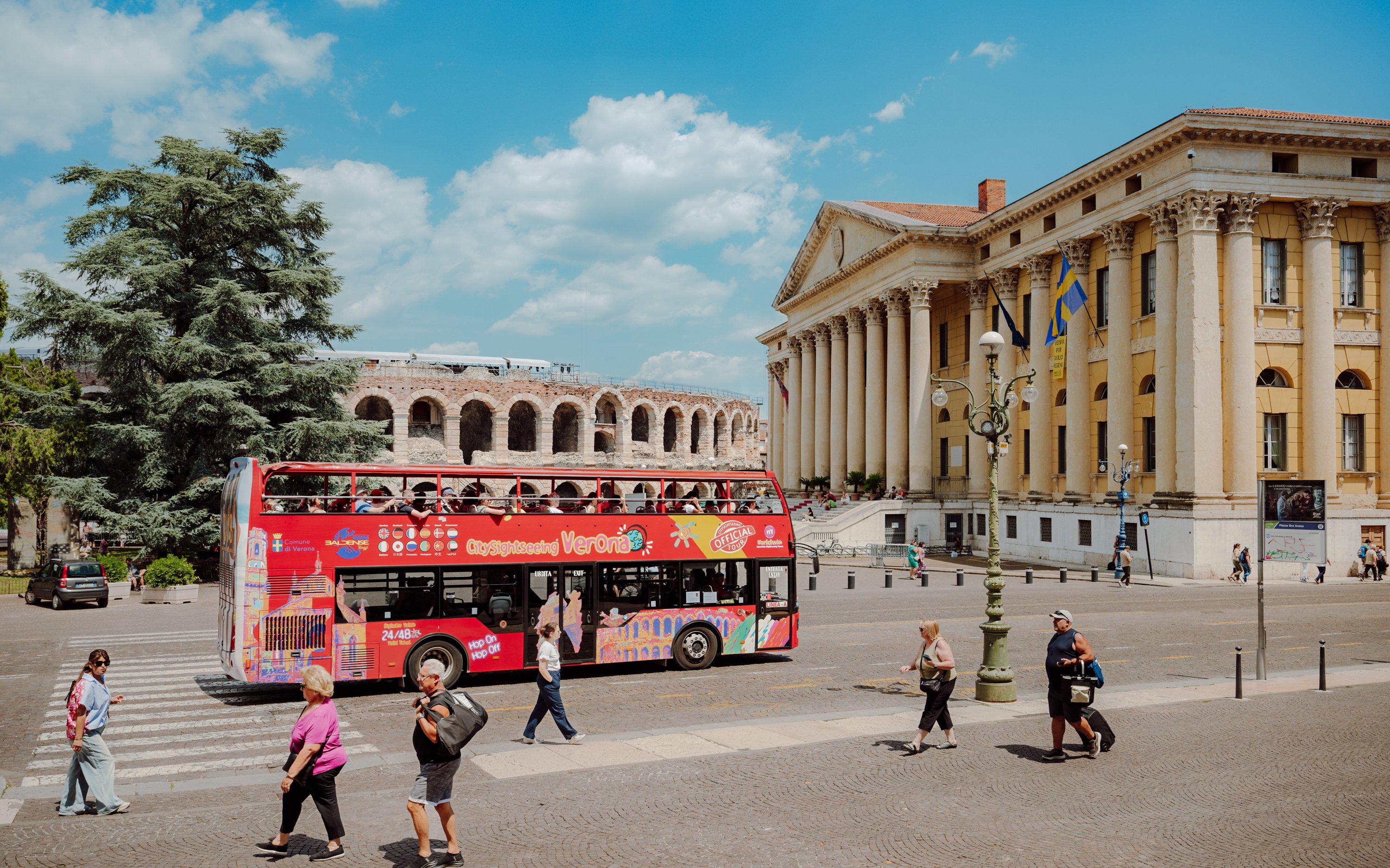 Red City Sightseeing Verona bus near Verona Arena and Palazzo Barbieri.