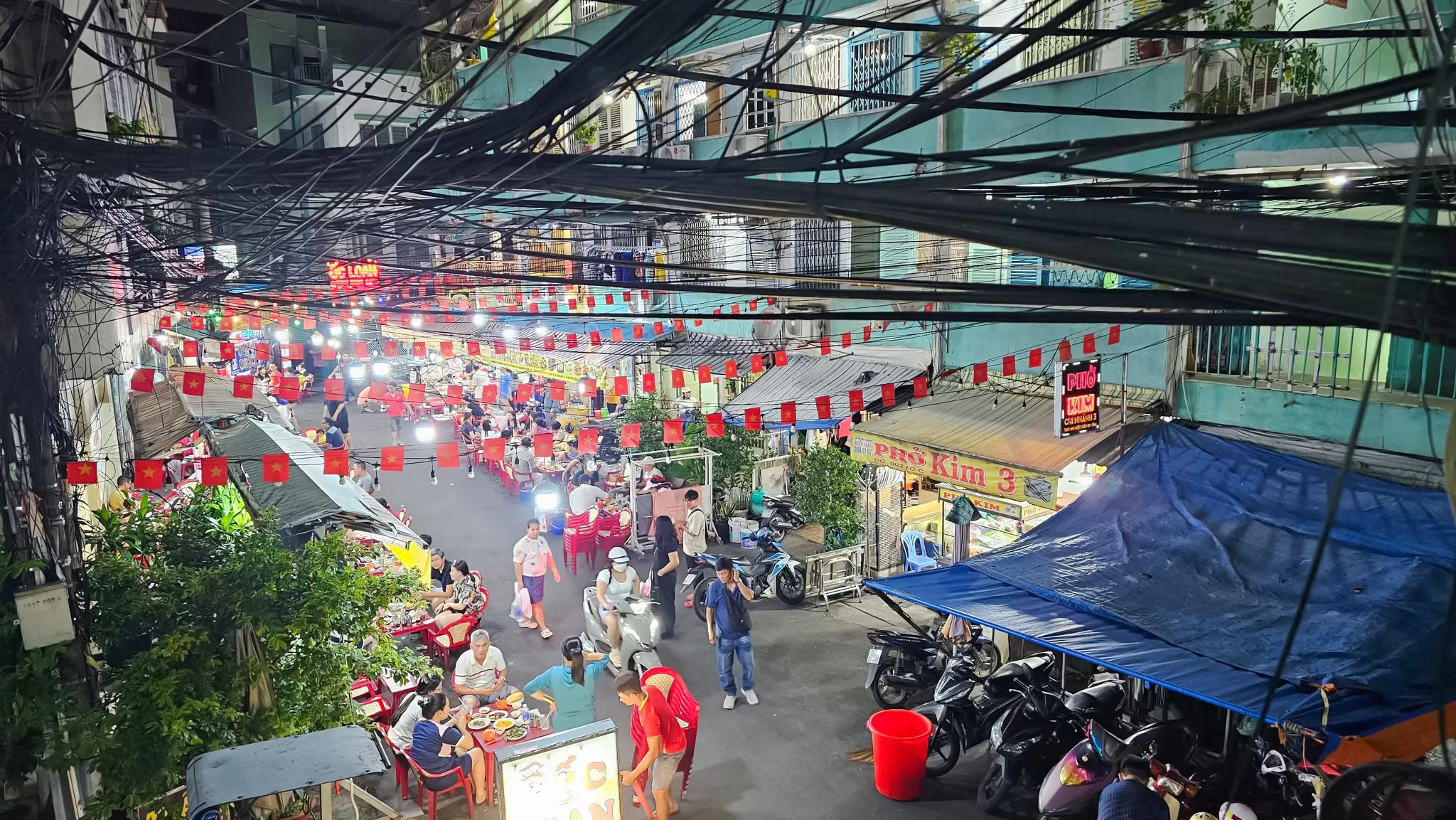 Saigon street food market with people dining and motorbikes, Ho Chi Minh City.