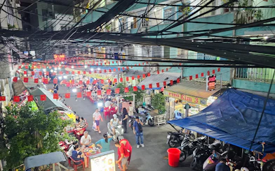 Saigon street food market with people dining and motorbikes, Ho Chi Minh City.