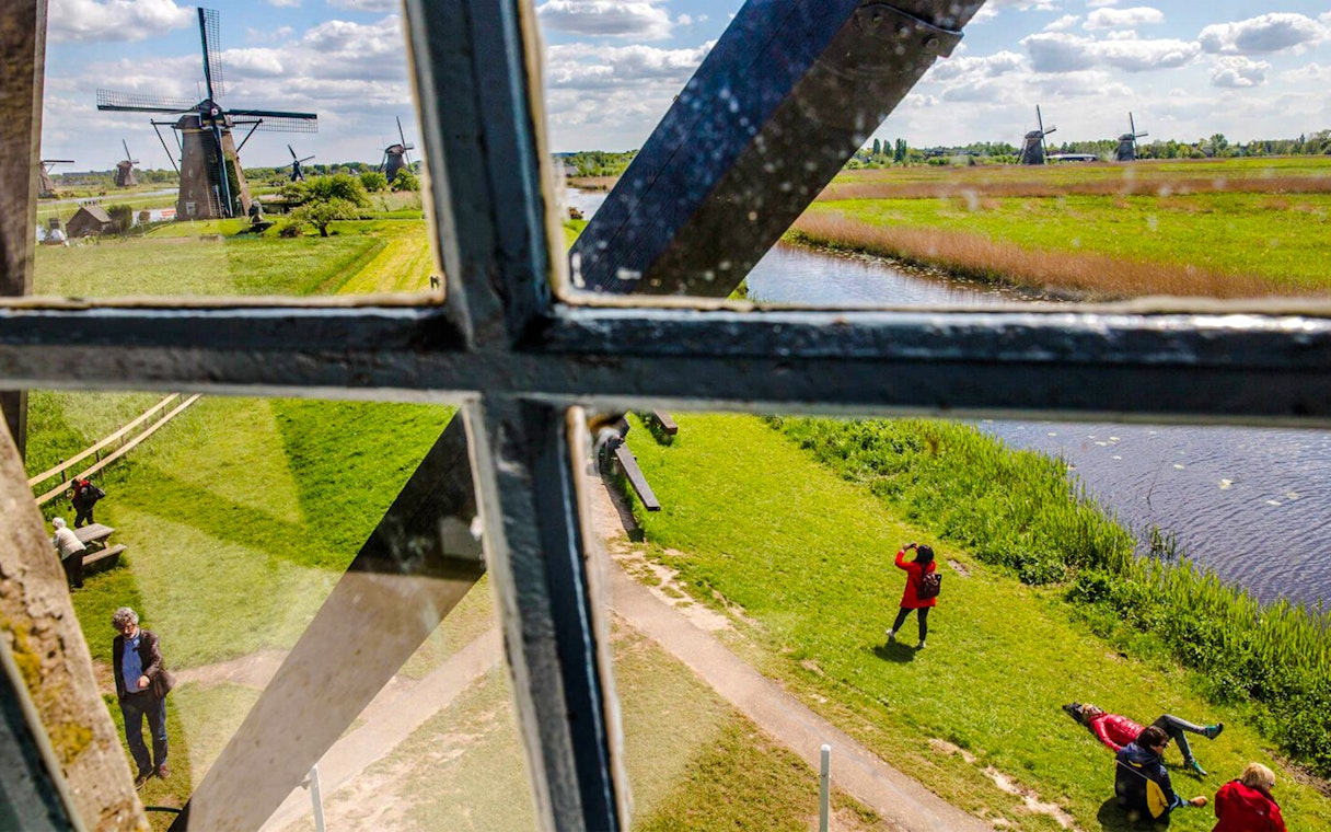 View from inside Nederwaard Museum Mill at Kinderdijk, showing windmills and visitors outside.
