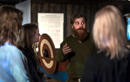 Guide explaining Viking history to visitors at Stockholm museum.