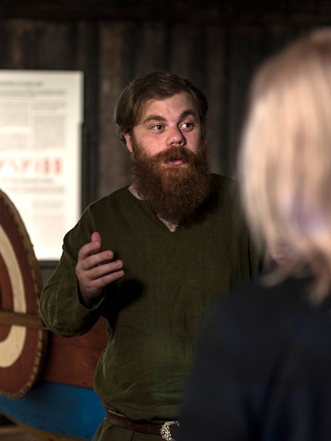 Guide explaining Viking history to visitors at Stockholm museum.