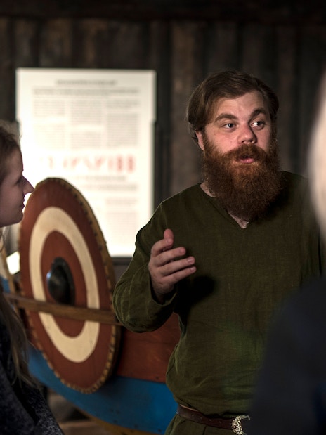 Guide explaining Viking history to visitors at Stockholm museum.