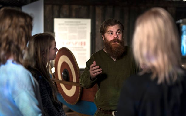 Guide explaining Viking history to visitors at Stockholm museum.