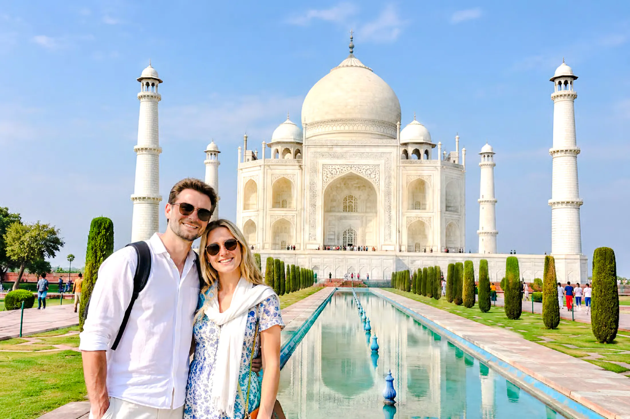 Couple in front of the Taj Mahal reflecting in the pool, Agra, India.