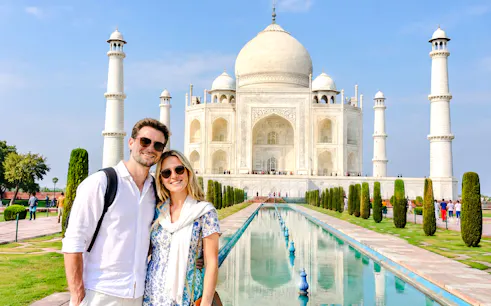 Couple in front of the Taj Mahal reflecting in the pool, Agra, India.