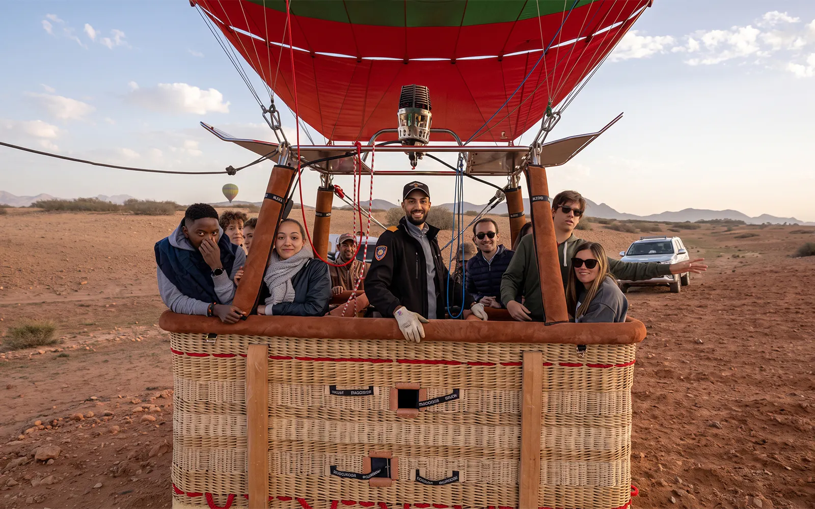 Hot air balloon passengers ready for sunrise flight over Marrakesh desert.