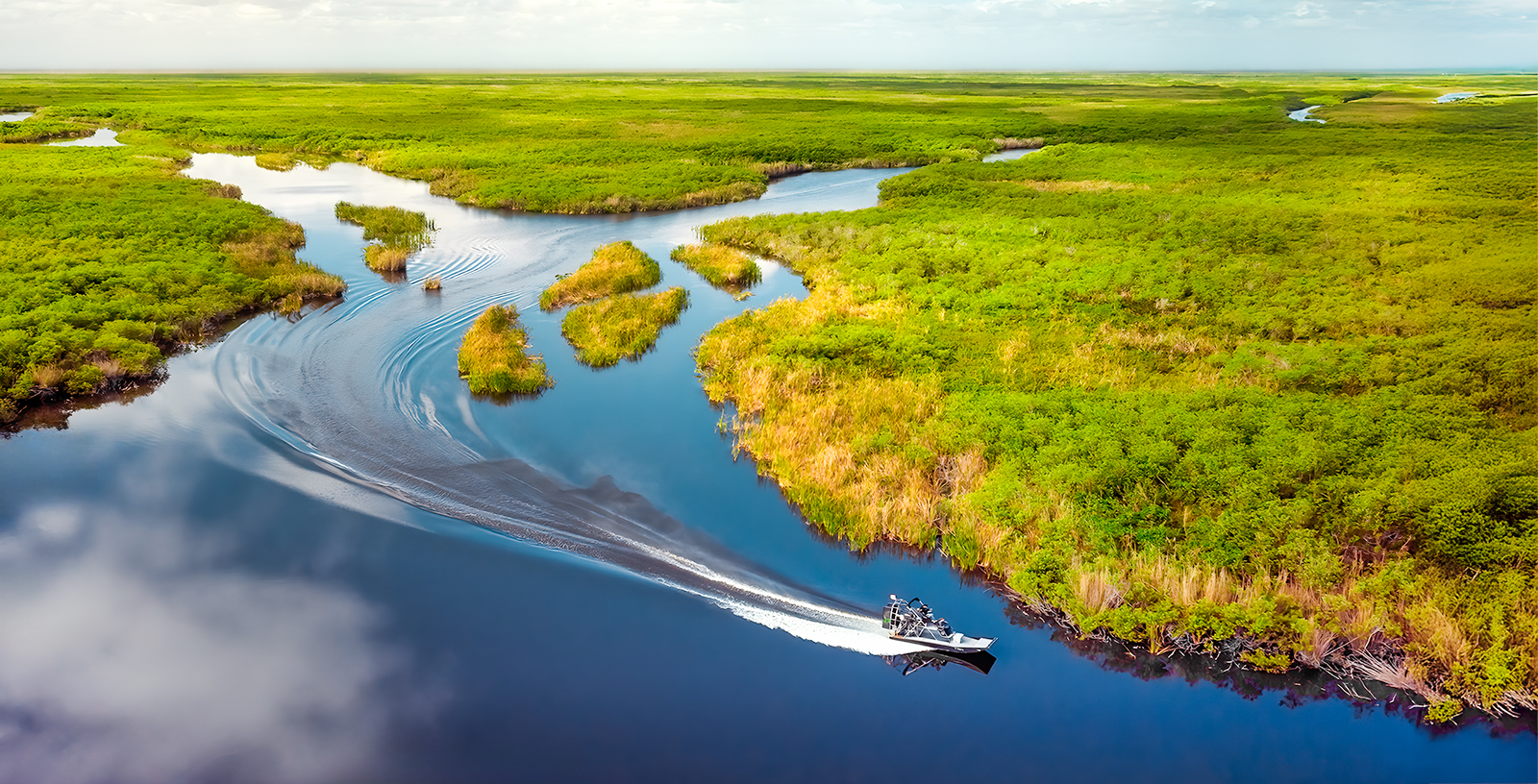 Aerial view of Florida Everglades with a boat navigating through lush wetlands.