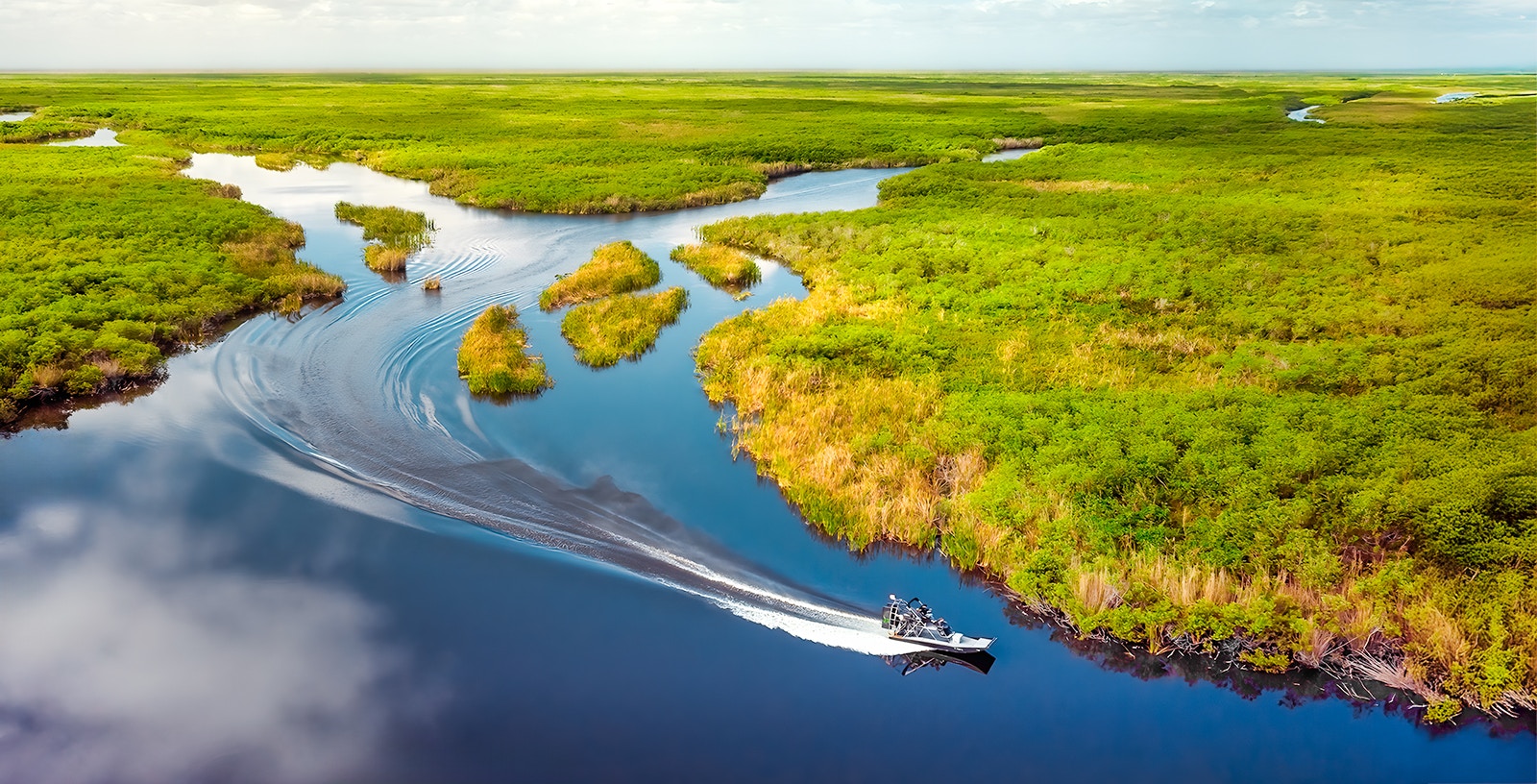 Aerial view of Florida Everglades with a boat navigating through lush wetlands.