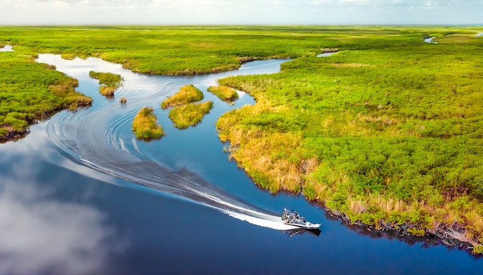 Aerial view of Florida Everglades with a boat navigating through lush wetlands.
