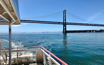Cruise boat under Bay Bridge on Golden Gate Bay.