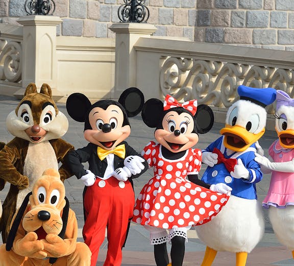 Characters at Disneyland Paris in front of a castle wall.