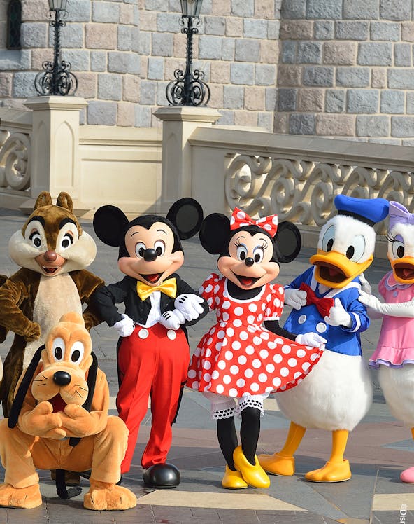 Characters at Disneyland Paris in front of a castle wall.