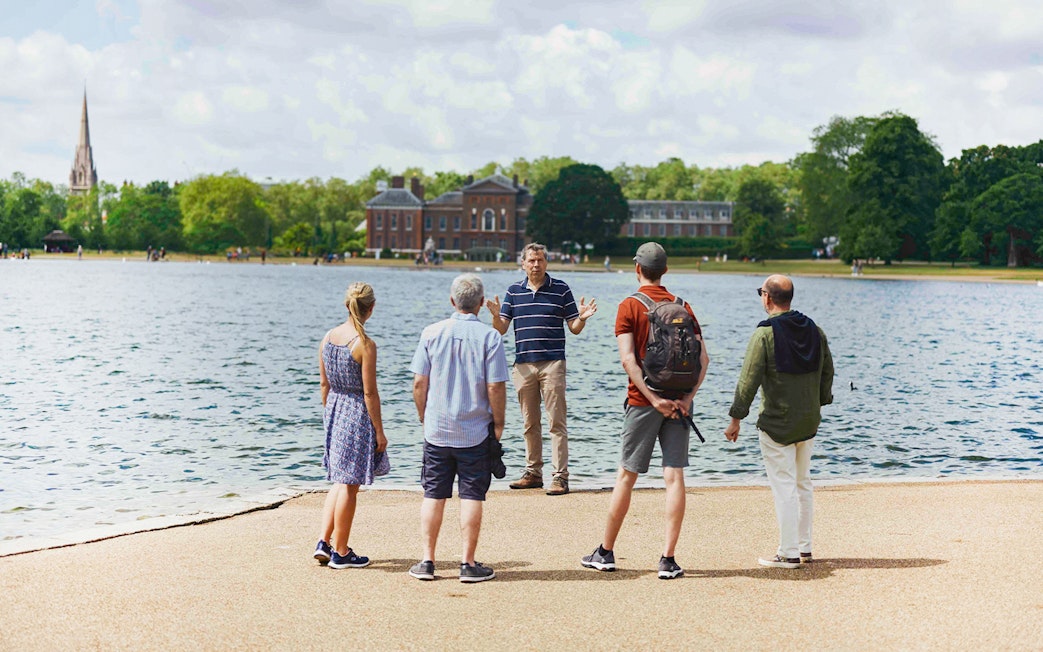 Tour group by Kensington Palace lake, listening to a guide during the Royal Afternoon Tea experience.