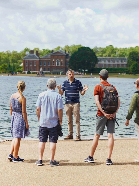 Tour group by Kensington Palace lake, listening to a guide during the Royal Afternoon Tea experience.