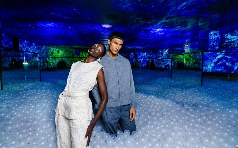 Couple standing in immersive AYA Universe exhibit with glowing blue and green lights.