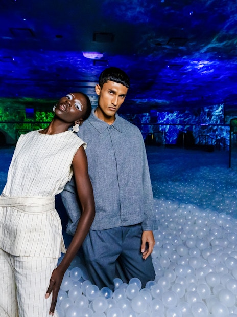 Couple standing in immersive AYA Universe exhibit with glowing blue and green lights.