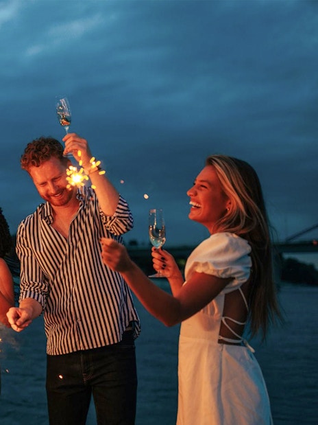 Guests celebrating with sparklers on an evening cruise along Athens Riviera.