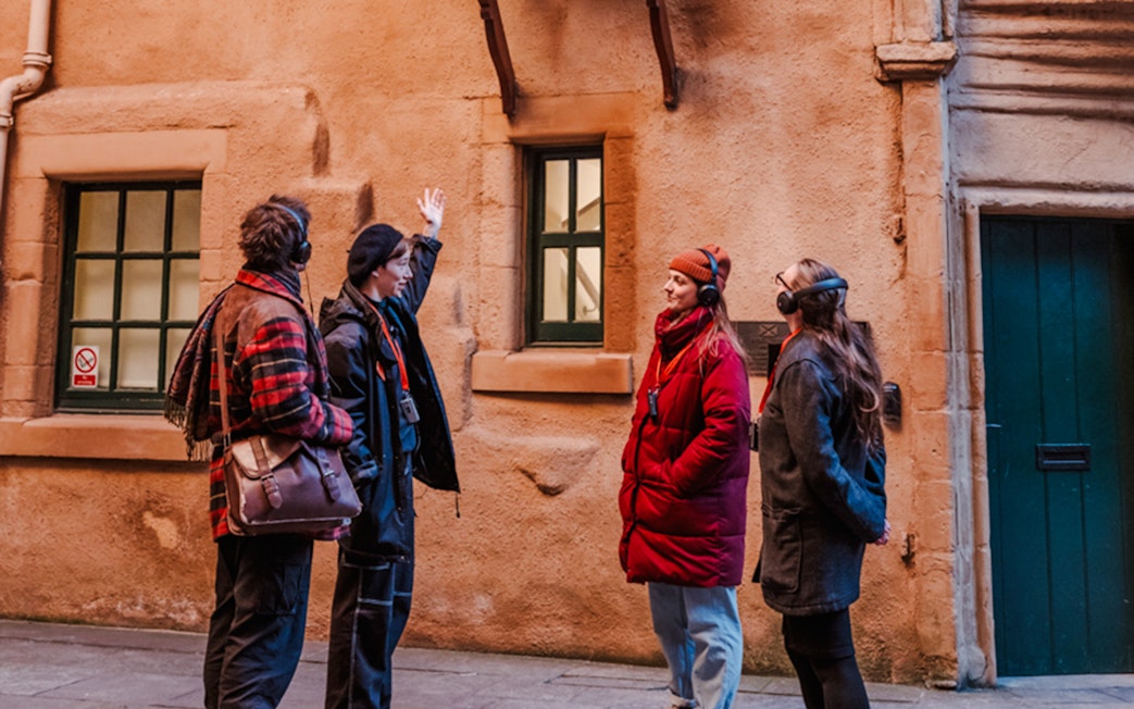 Tour guide explaining historical site on Edinburgh's Royal Mile to visitors.