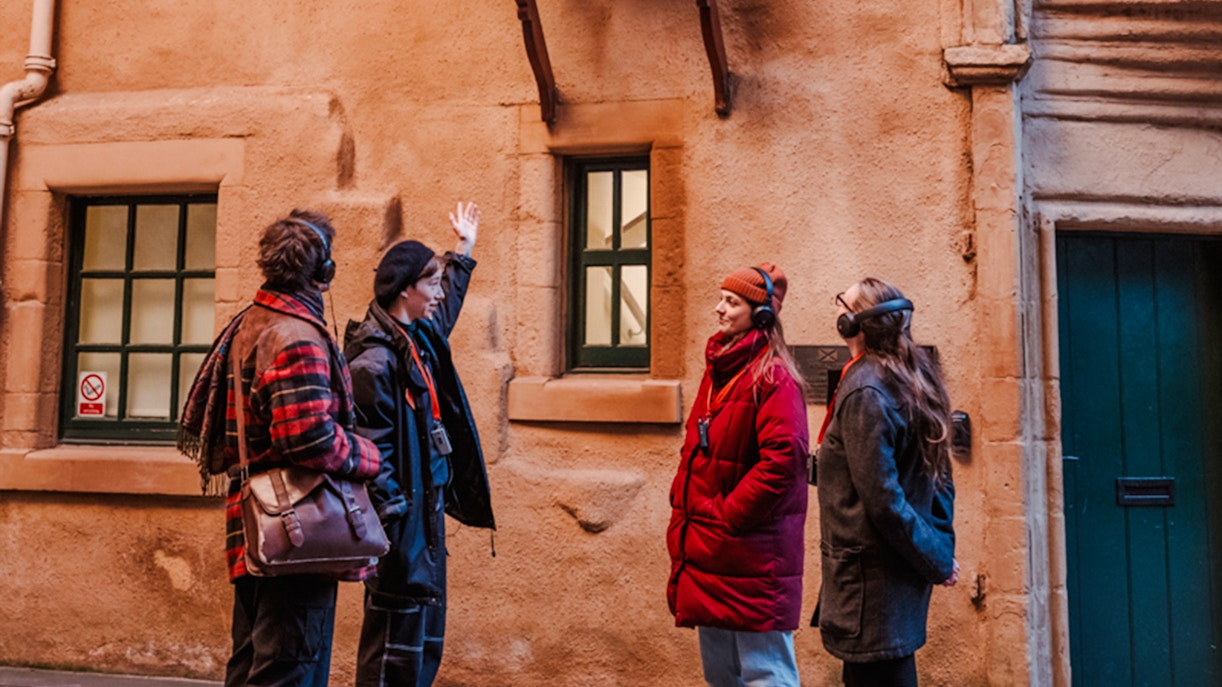 Tour guide explaining historical site on Edinburgh's Royal Mile to visitors.