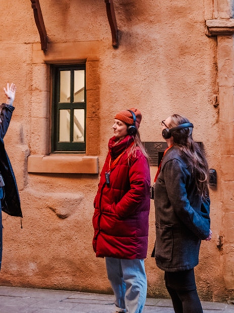 Tour guide explaining historical site on Edinburgh's Royal Mile to visitors.
