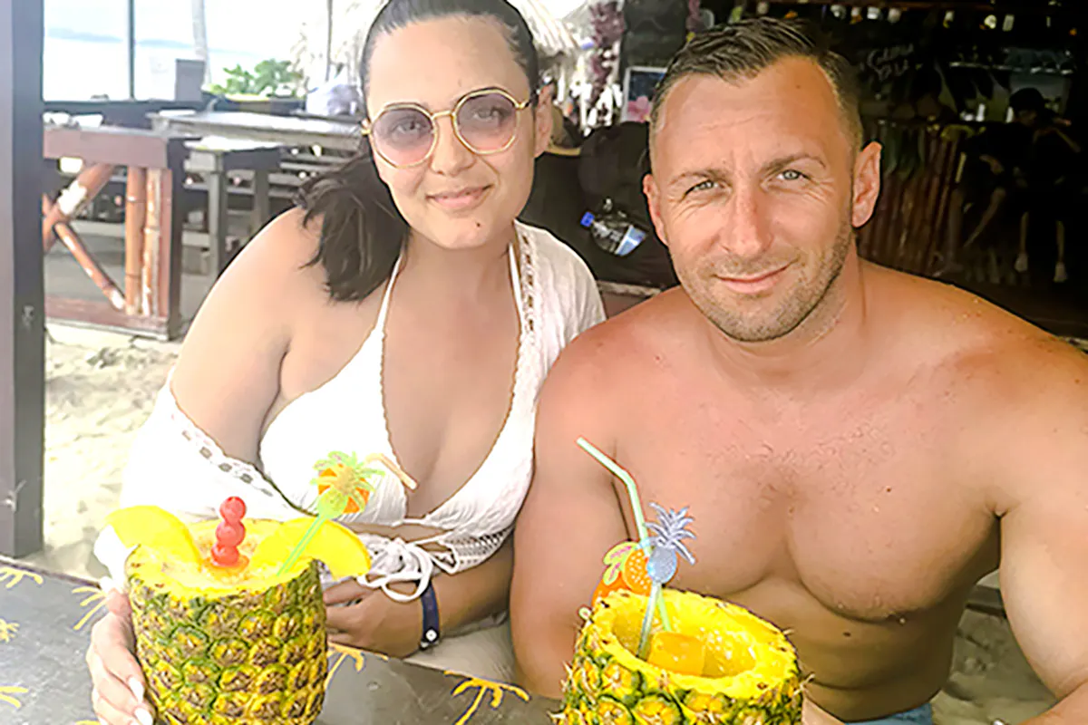 Couple enjoying tropical drinks in pineapples on Islas de San Blas tour, Panama City.
