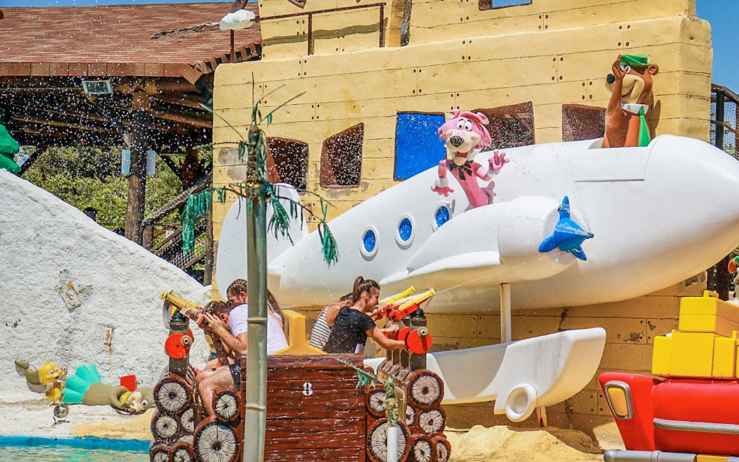 Parque Warner Madrid water ride with cartoon characters and visitors spraying water.