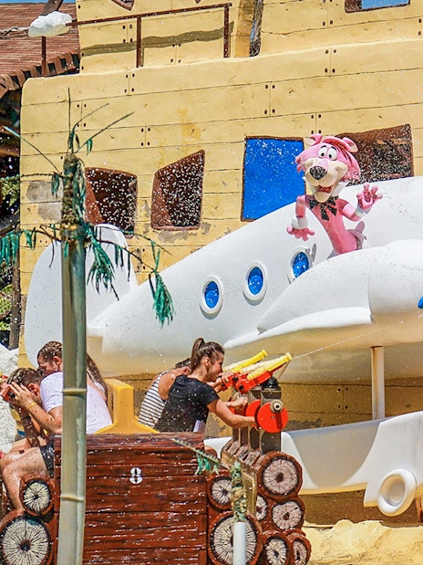 Parque Warner Madrid water ride with cartoon characters and visitors spraying water.