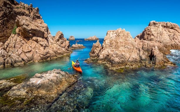 Visitors kayaking through rocky waters at Costa Brava.