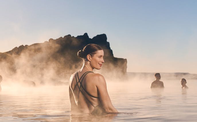 Guests enjoying the warm waters at Sky Lagoon with mist and rocky backdrop.