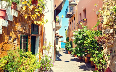 Narrow alley in Chania, Crete with colorful buildings and lush plants.