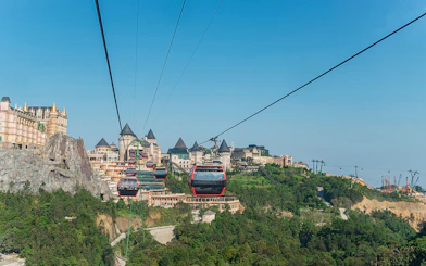Cable cars traveling to Ba Na Hills in Da Nang, Vietnam with castle-like structures in view.