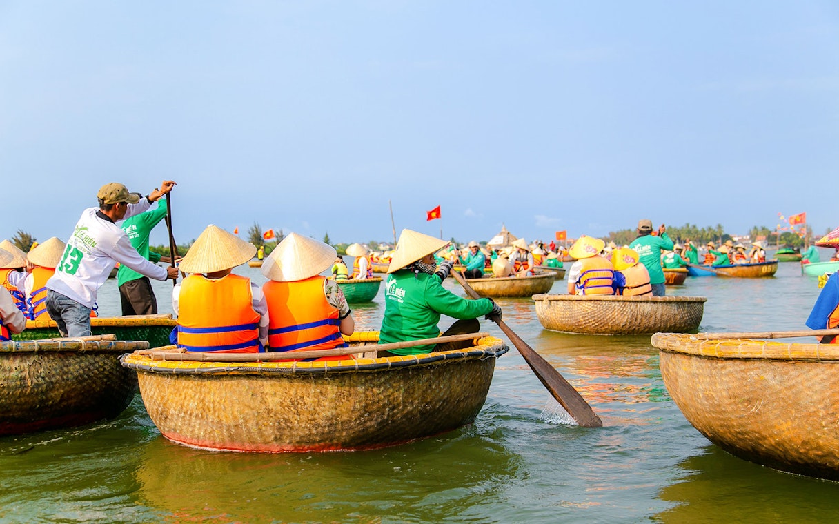 Bamboo basket boats navigating a river in a coconut palm forest tour.