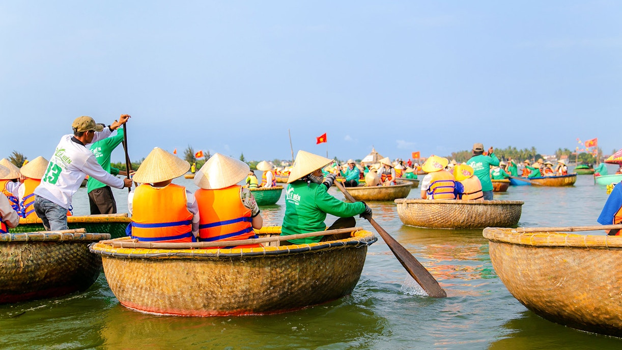 Bamboo basket boats navigating a river in a coconut palm forest tour.