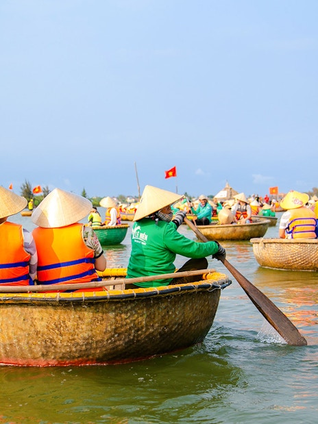 Bamboo basket boats navigating a river in a coconut palm forest tour.