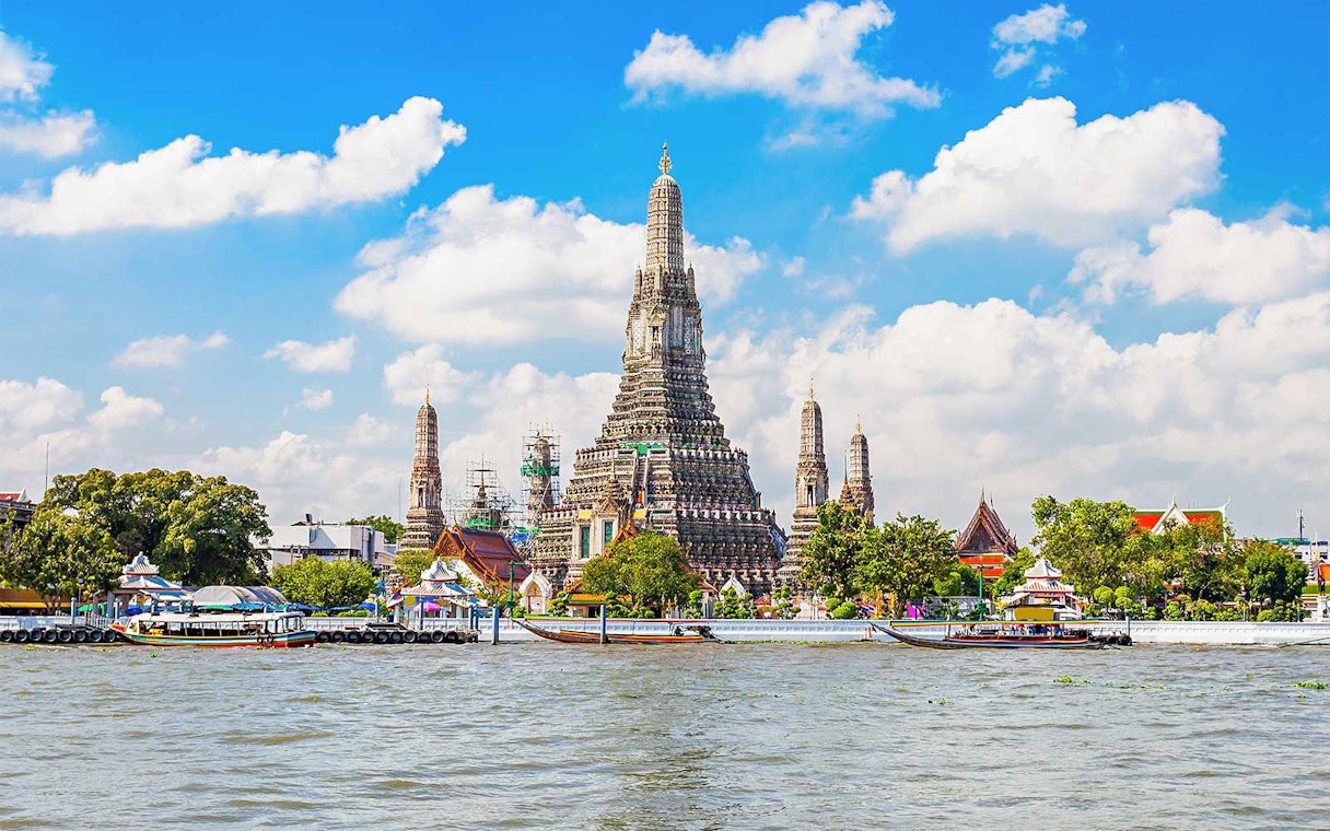 Wat Arun temple on Chao Phraya River, Bangkok, with boats in foreground.