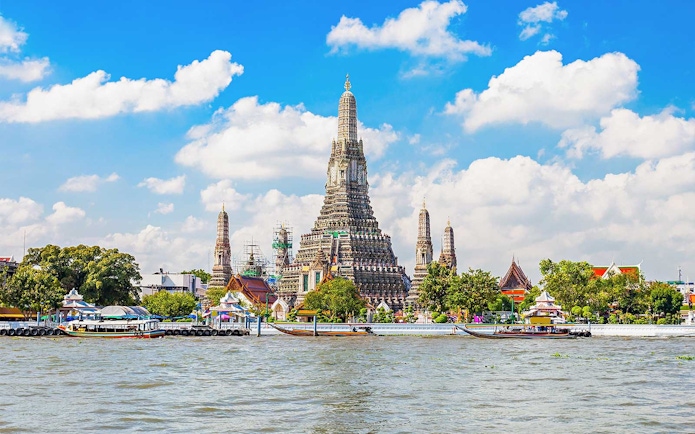 Wat Arun temple on Chao Phraya River, Bangkok, with boats in foreground.