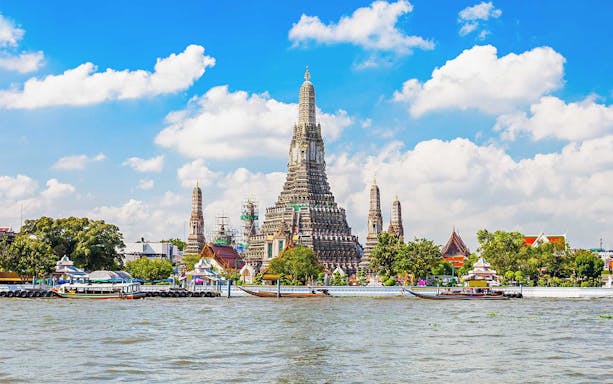 Wat Arun temple on Chao Phraya River, Bangkok, with boats in foreground.