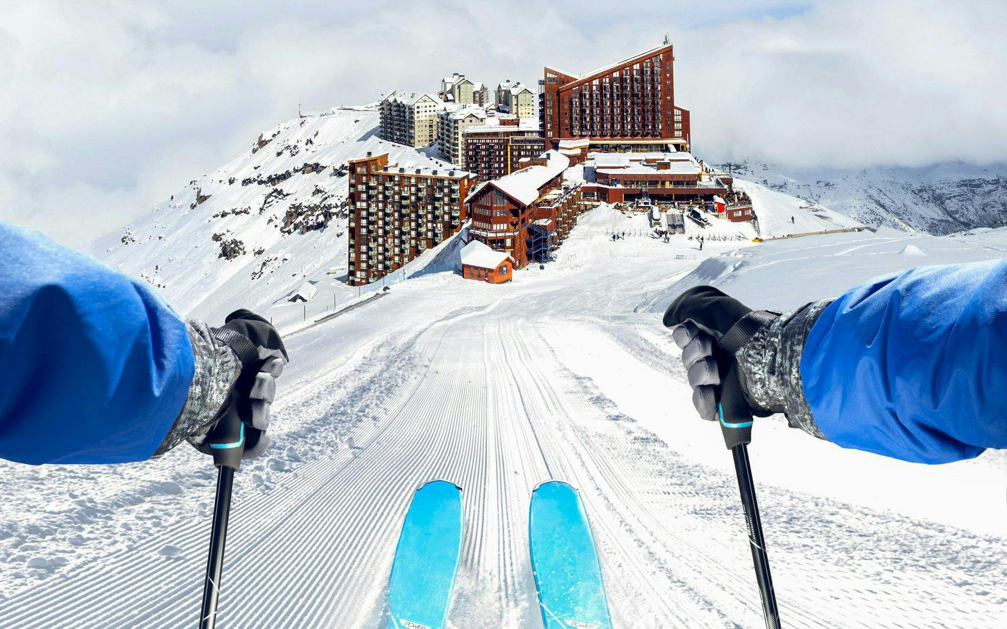 Skier descending a slope at Valle Nevado ski resort, Chile, with mountain view.