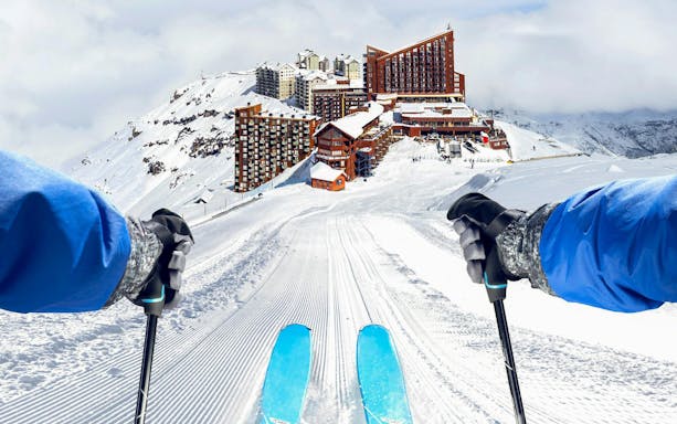 Skier descending a slope at Valle Nevado ski resort, Chile, with mountain view.