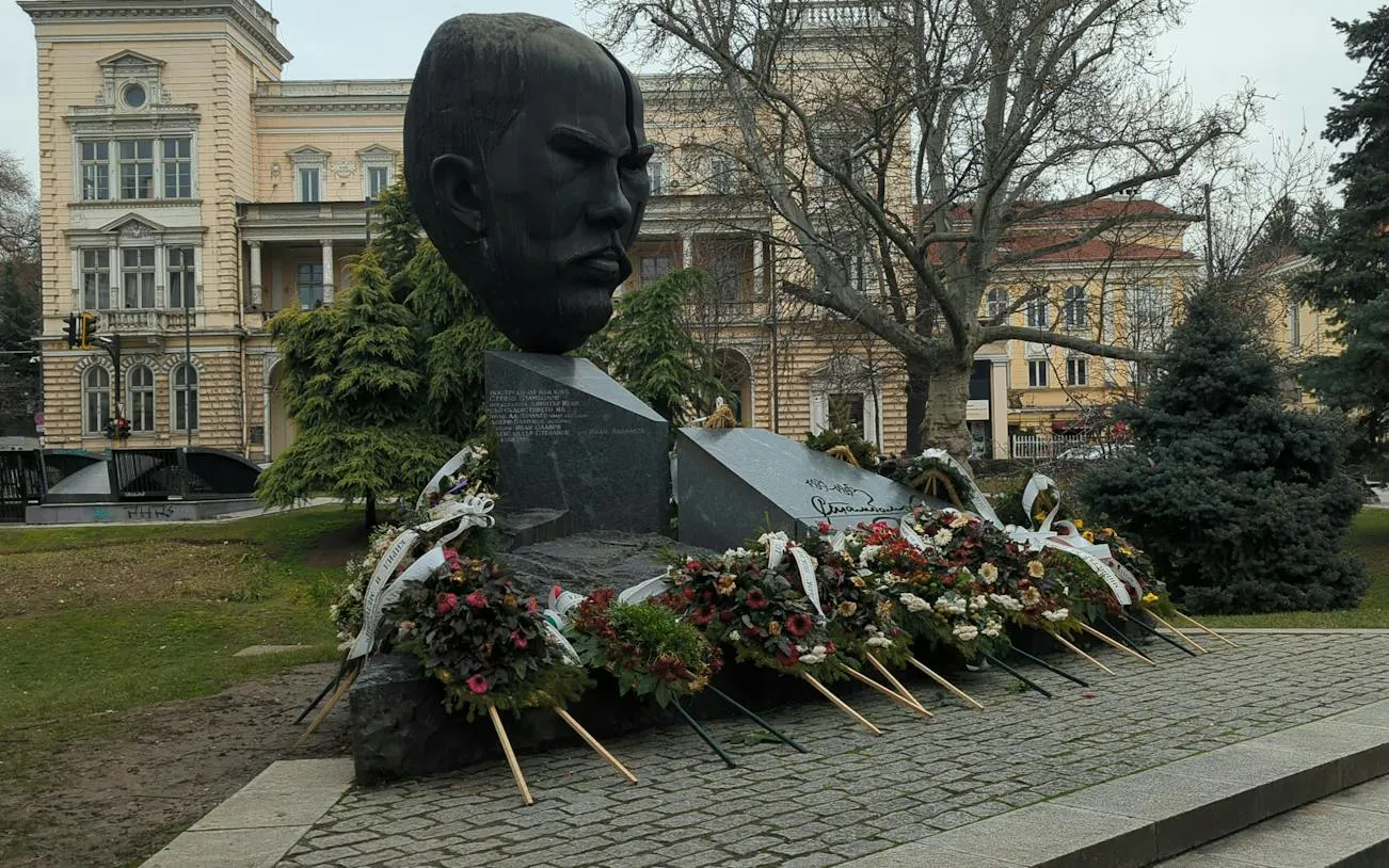 Bust monument with floral tributes in Sofia, part of Sofia Obscura Secrets exploration game.