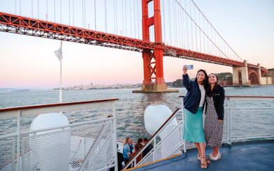 Guests taking a selfie on a San Francisco dinner cruise with Golden Gate Bridge in the background.