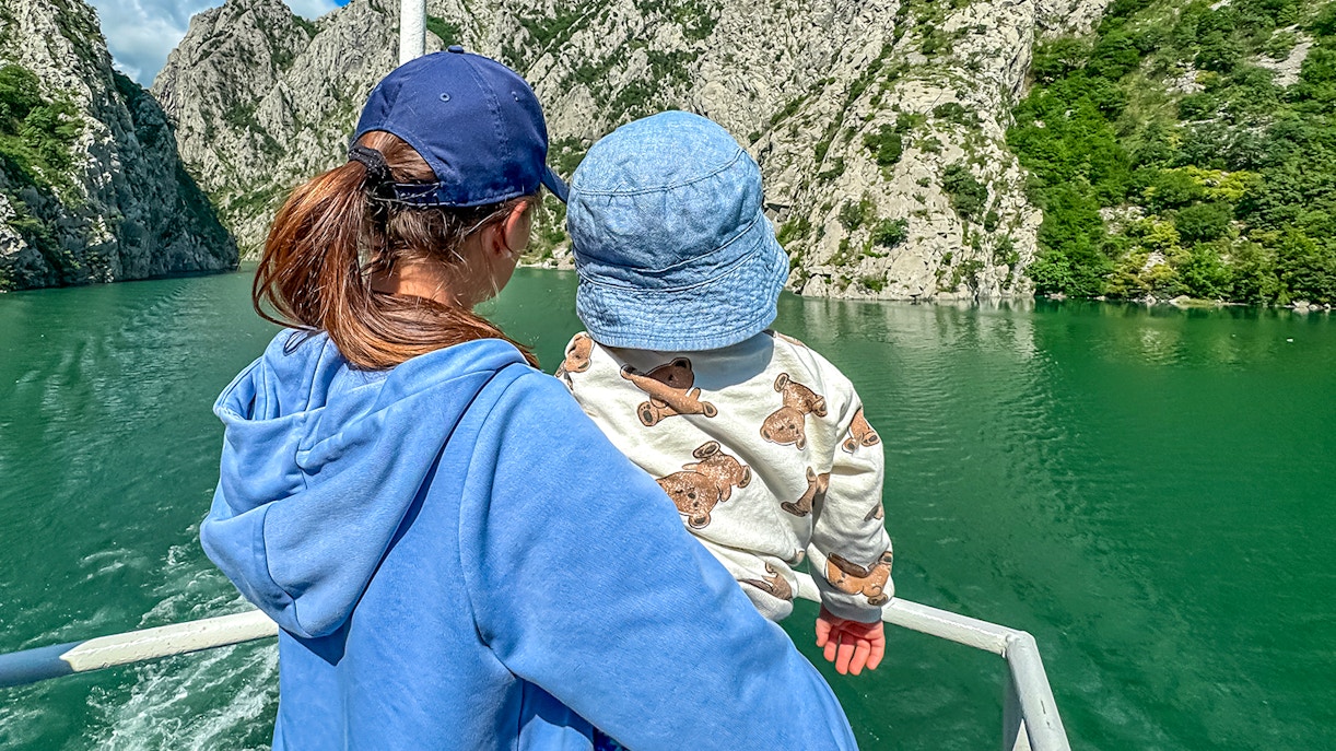 Mother and baby on a boat tour surrounded by rocky cliffs.
