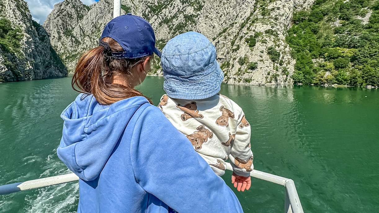 Mother and baby on a boat tour surrounded by rocky cliffs.