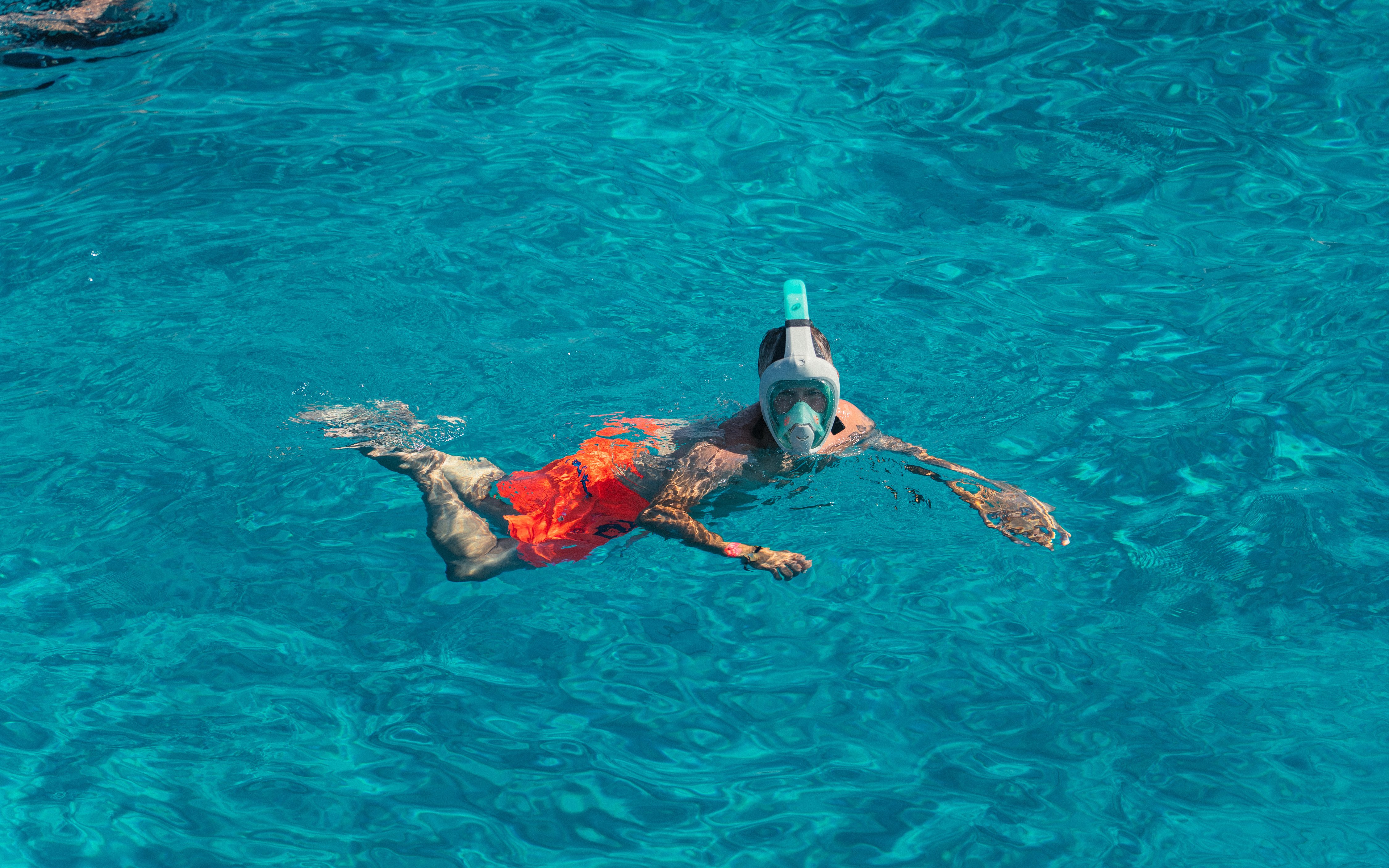 Snorkeler in clear blue water at Cala Bassa beach, Ibiza, Spain.