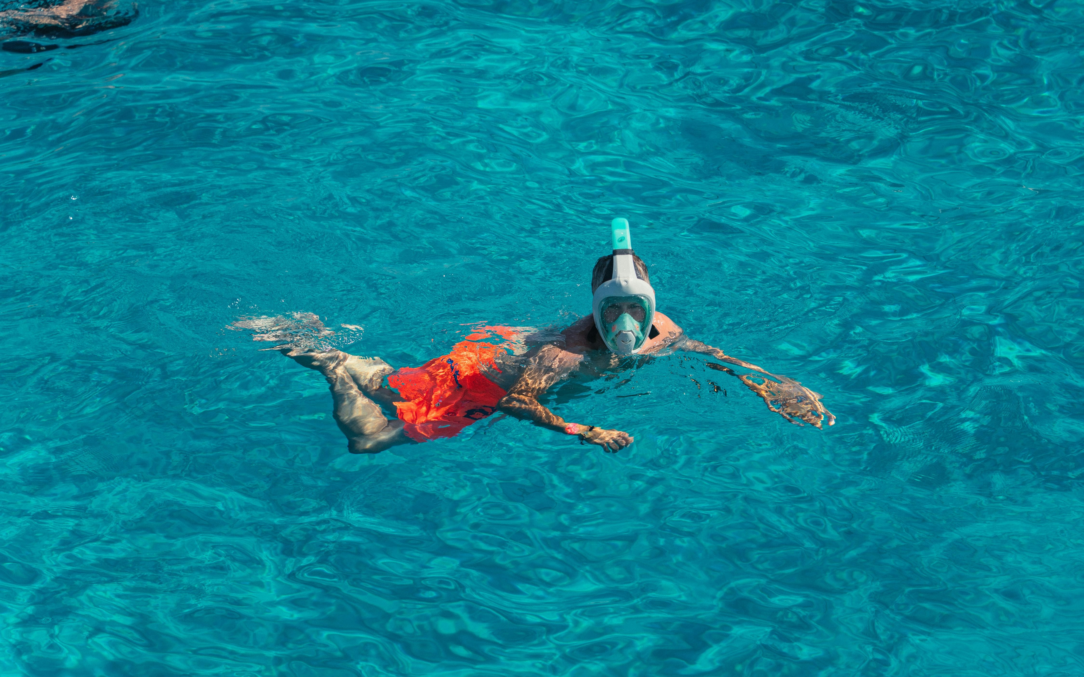 Snorkeler in clear blue water at Cala Bassa beach, Ibiza, Spain.
